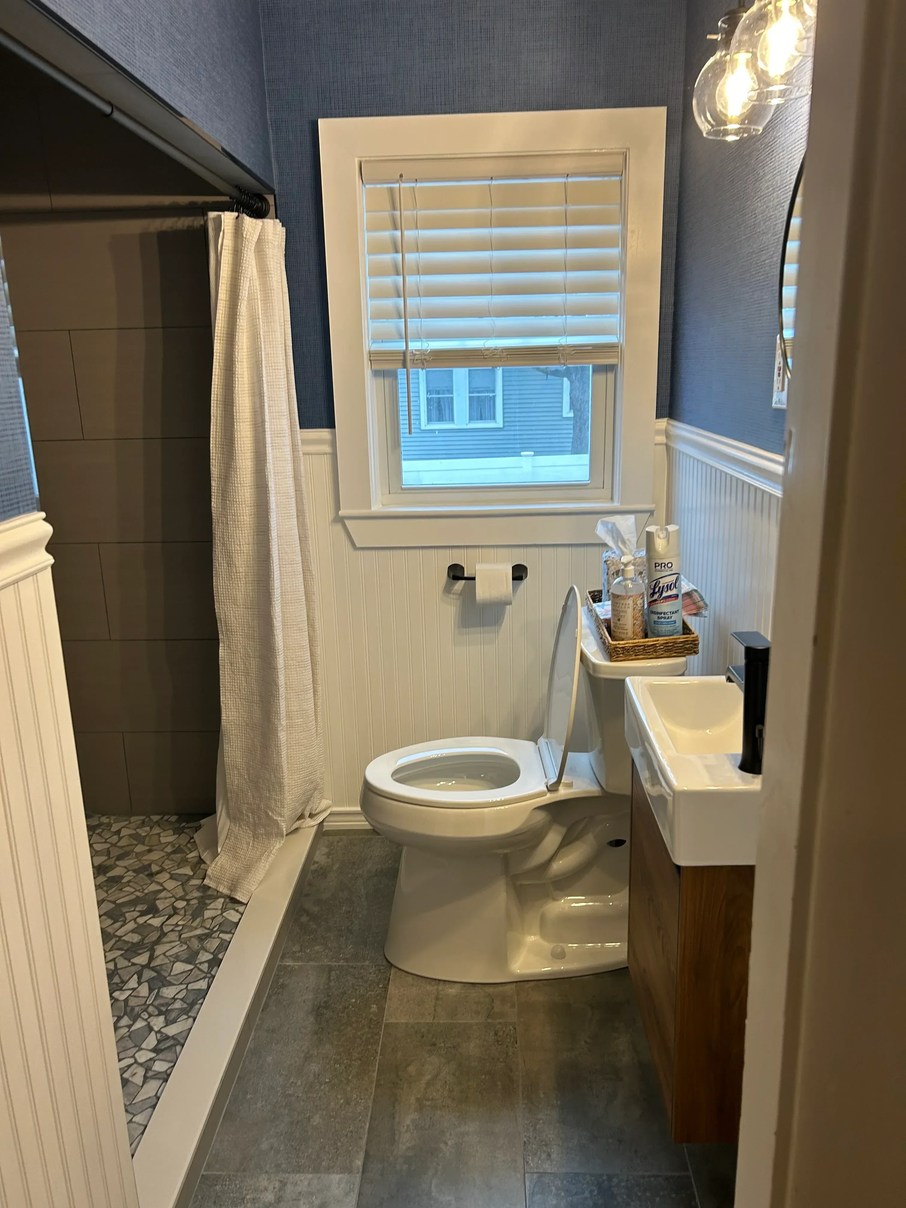 Bathroom with white vanity cabinet, dark subway tile wainscoting, and patterned tile accent