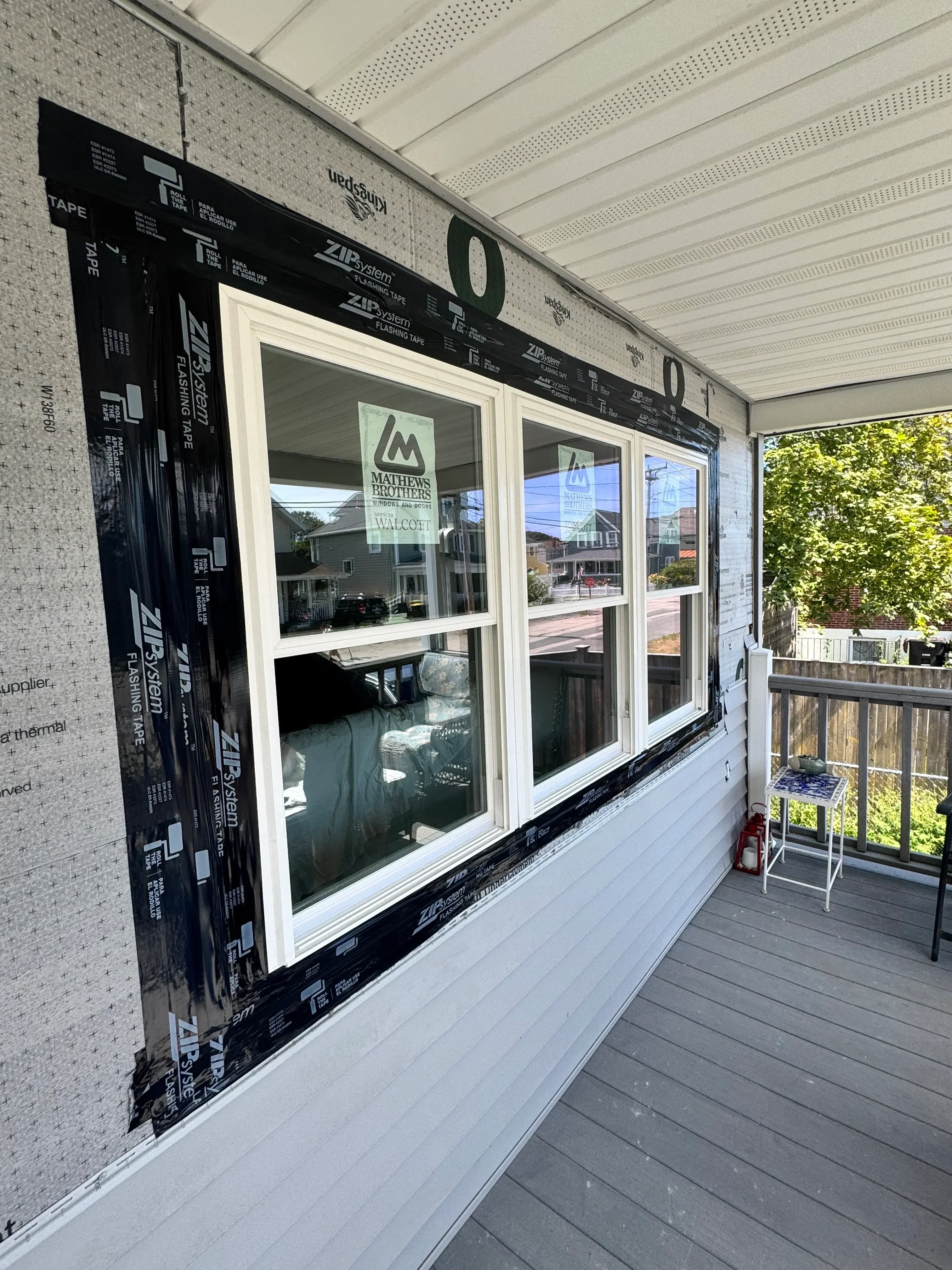 Three white vinyl double-hung windows installed with ZIP System flashing tape on exterior wall