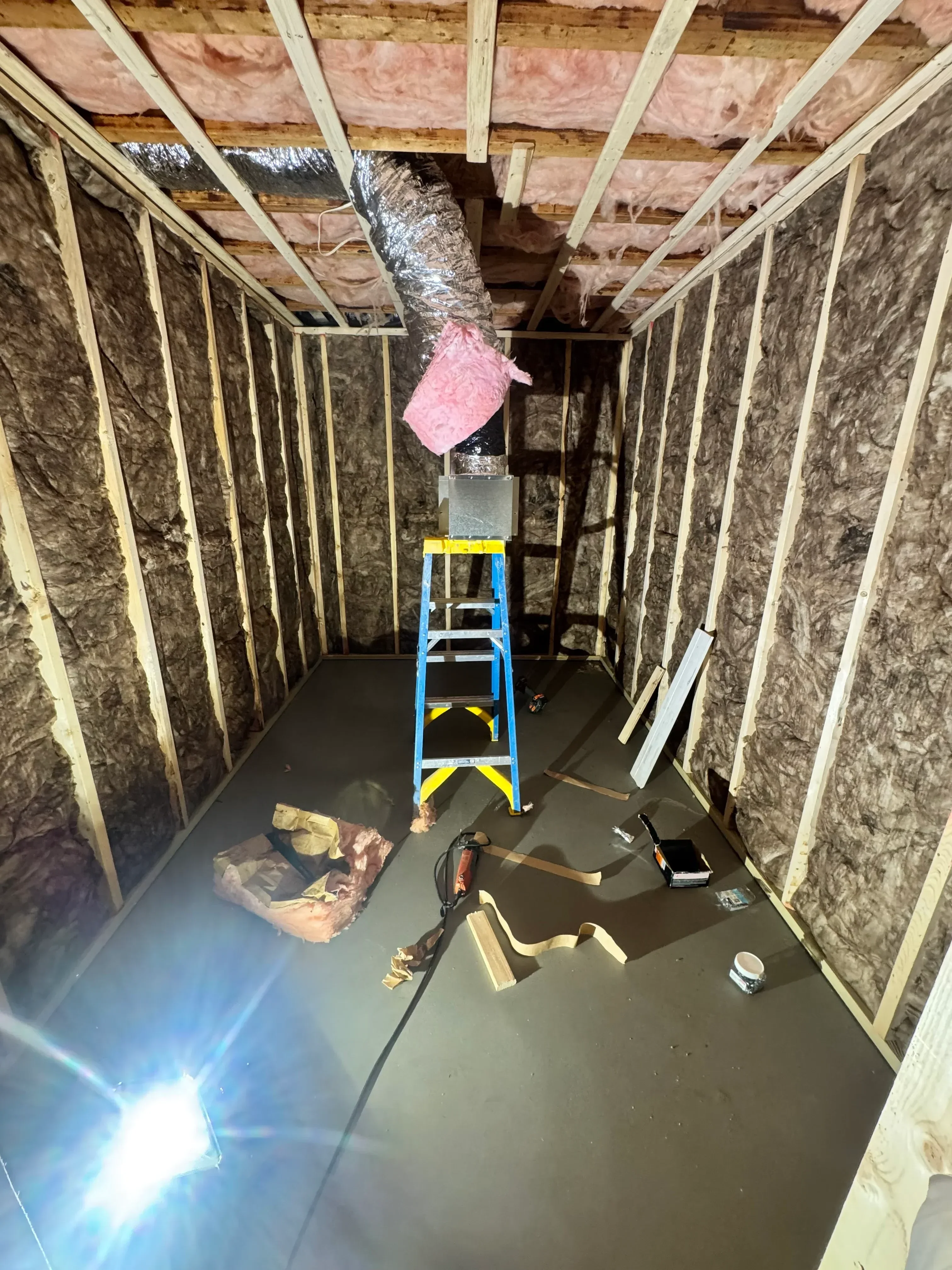 Attic framing with pink fiberglass insulation, wood joists, and drywall ceiling installation