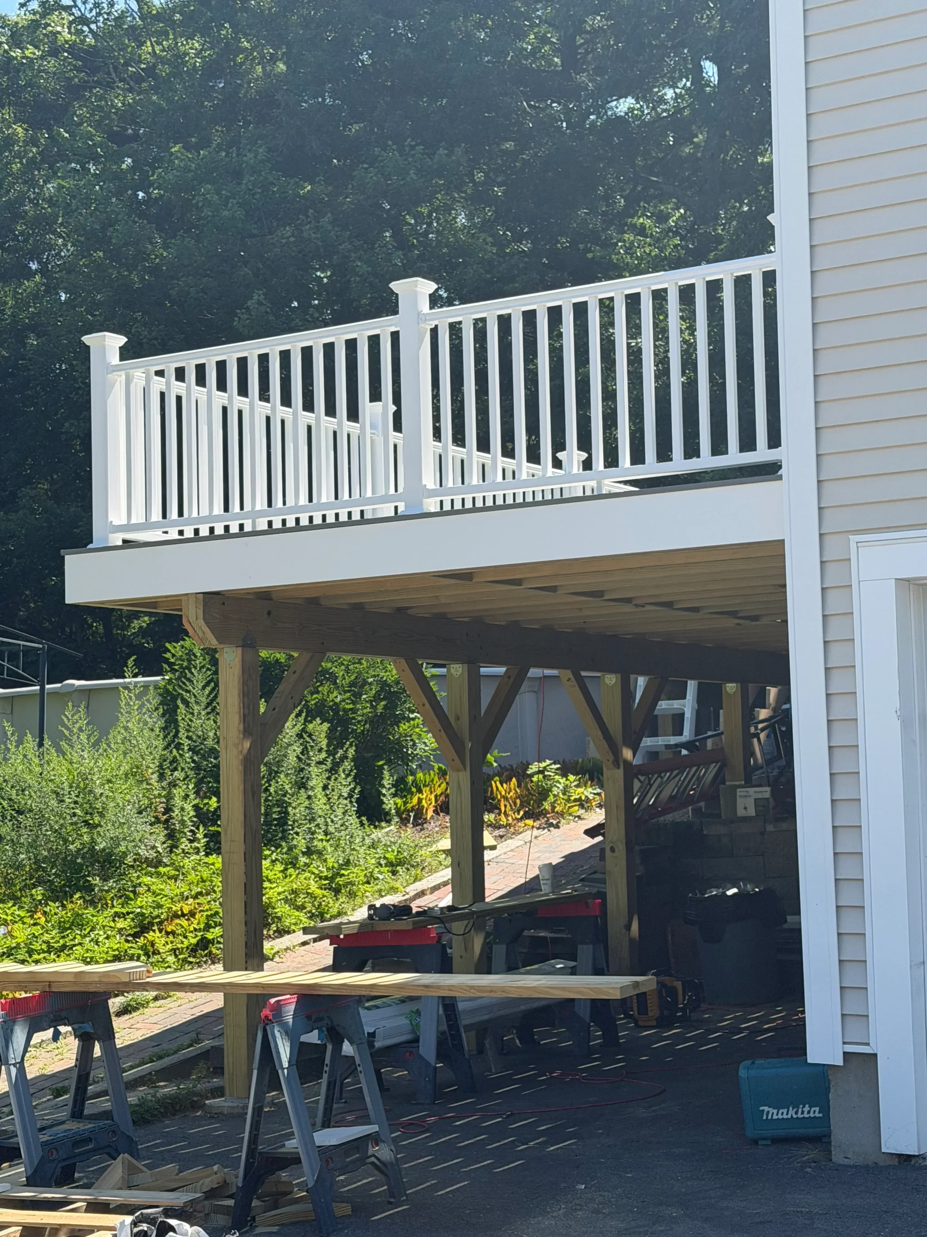 Elevated deck with pressure-treated wood frame, composite decking, white railings, and metal stair treads