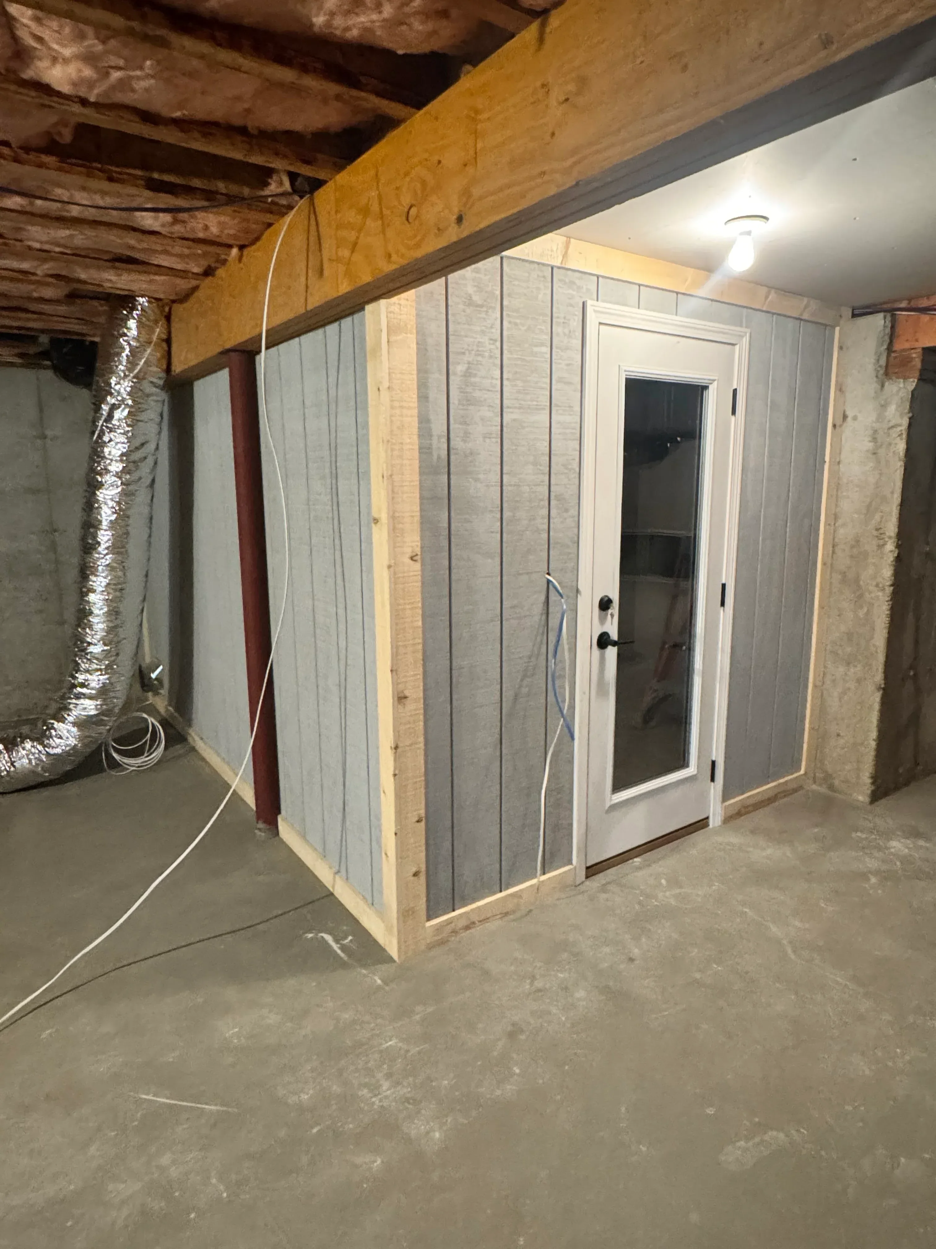 White vinyl basement window installed in concrete foundation wall with lumber framing