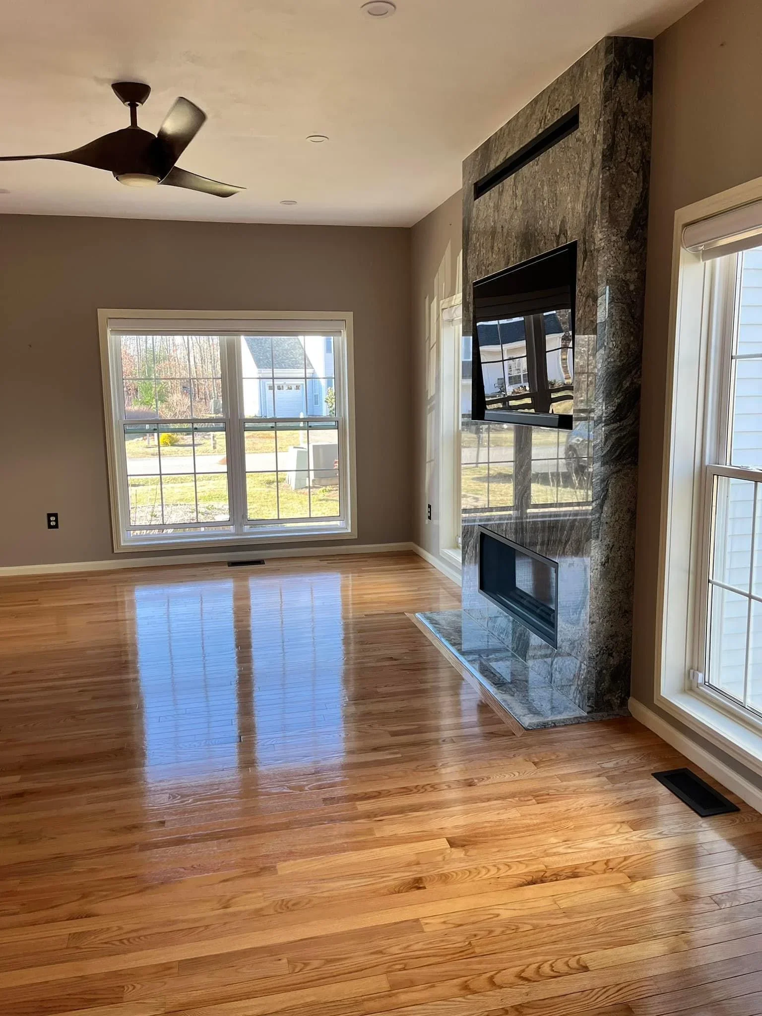 Polished hardwood floor with stone fireplace wall and linear fireplace insert in open living room