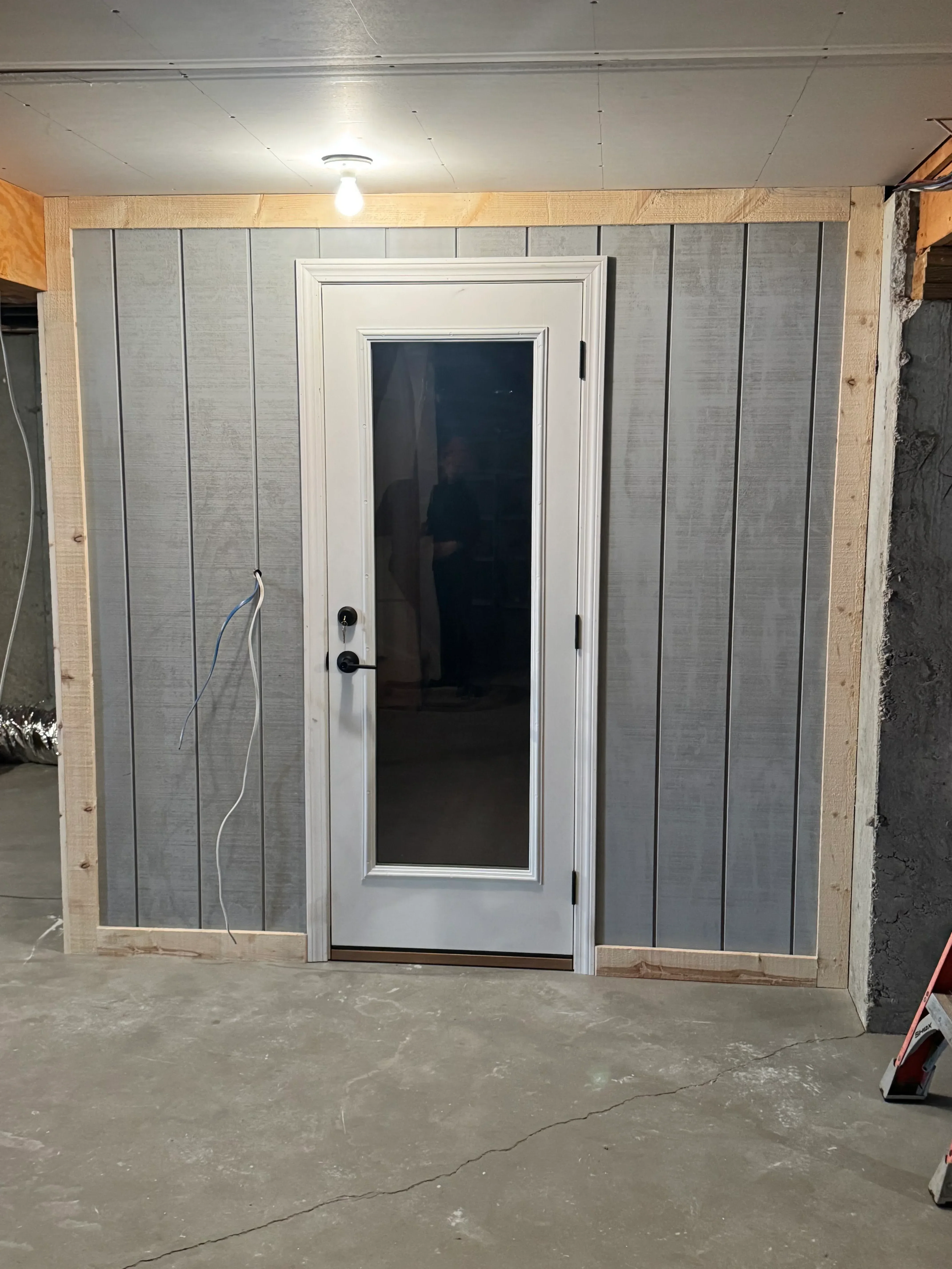 Gray sectional garage door with horizontal panels and white trim frame installed in wood opening