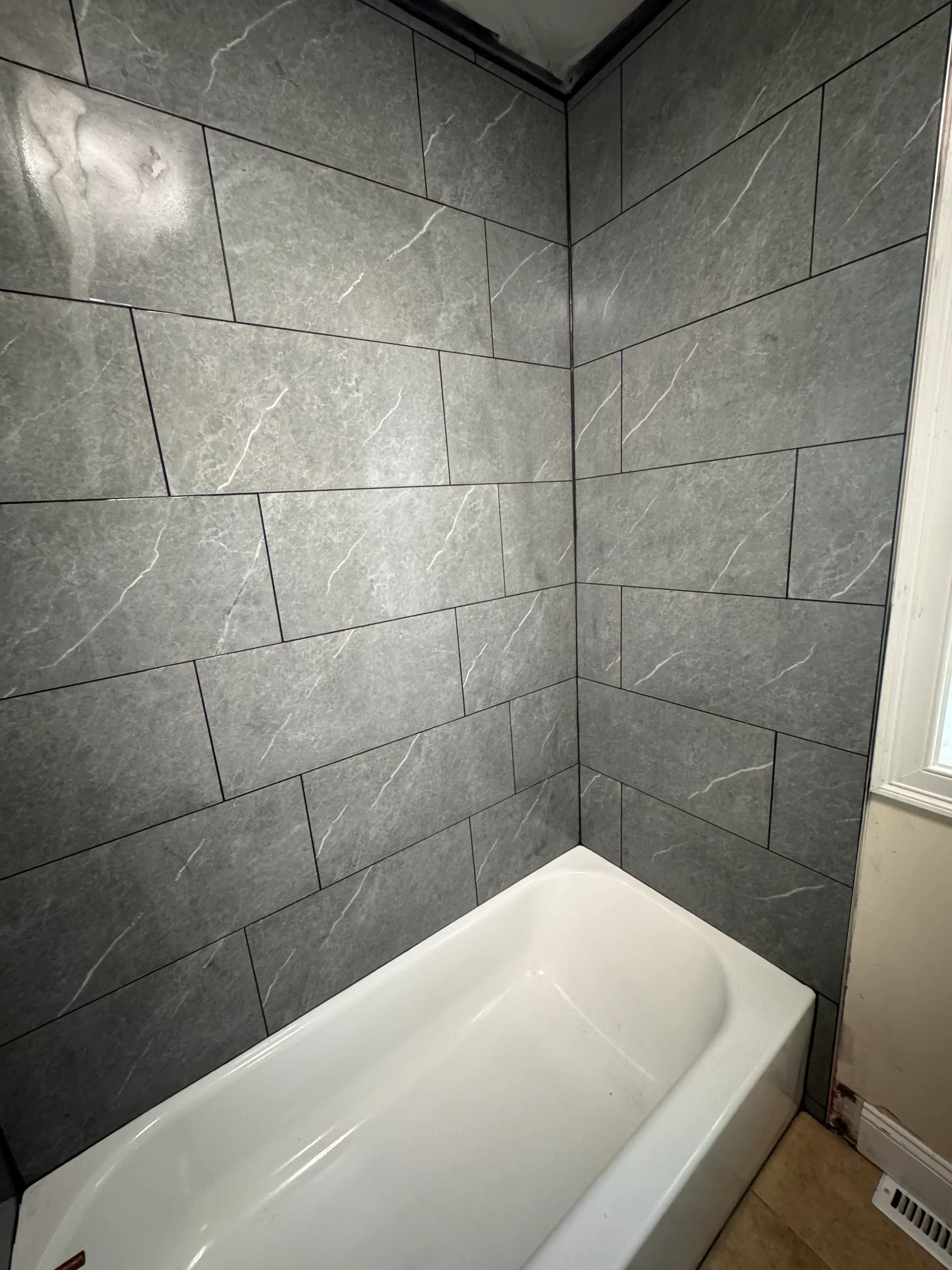 Gray marble-look porcelain floor tiles in staggered pattern with grout lines in bathroom