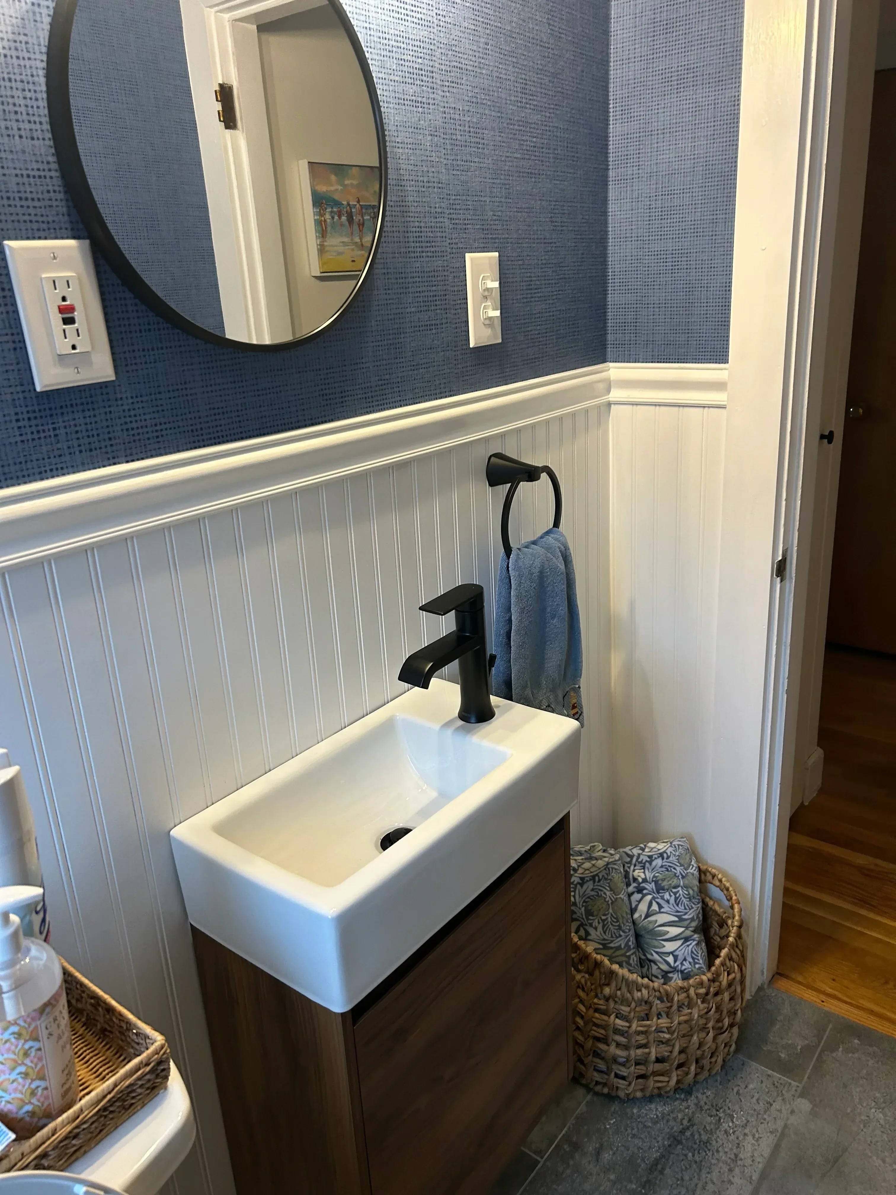 White pedestal sink with gray vinyl plank flooring and electrical outlets in renovated bathroom